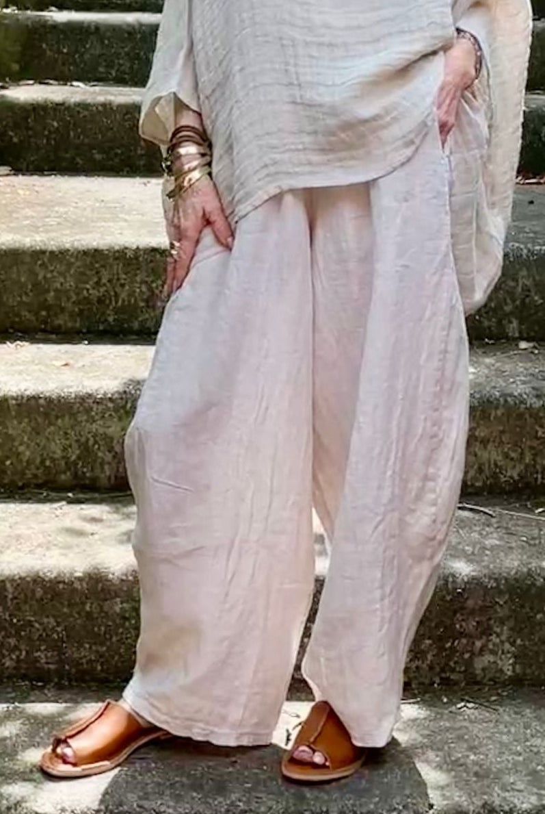 Woman in a light outfit standing on stone steps with greenery around